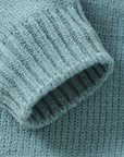 Detailed view of sleeve cuff on blue-green knitted baby romper highlighting soft stretch knit texture.