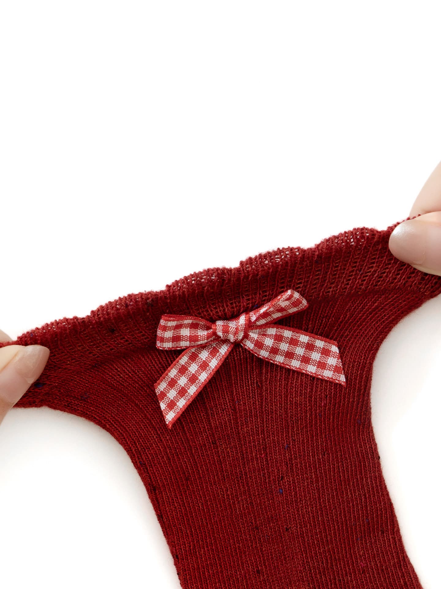 Close-up of soft stretchy red baby sock with checkered bow, seamless and skin-friendly fabric.
