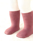 Toddler standing in thick pink cotton socks, cozy and breathable winter wear
