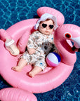 toddler wearing animal print rash guard swimsuit playing with sand at the beach UV swimwear
