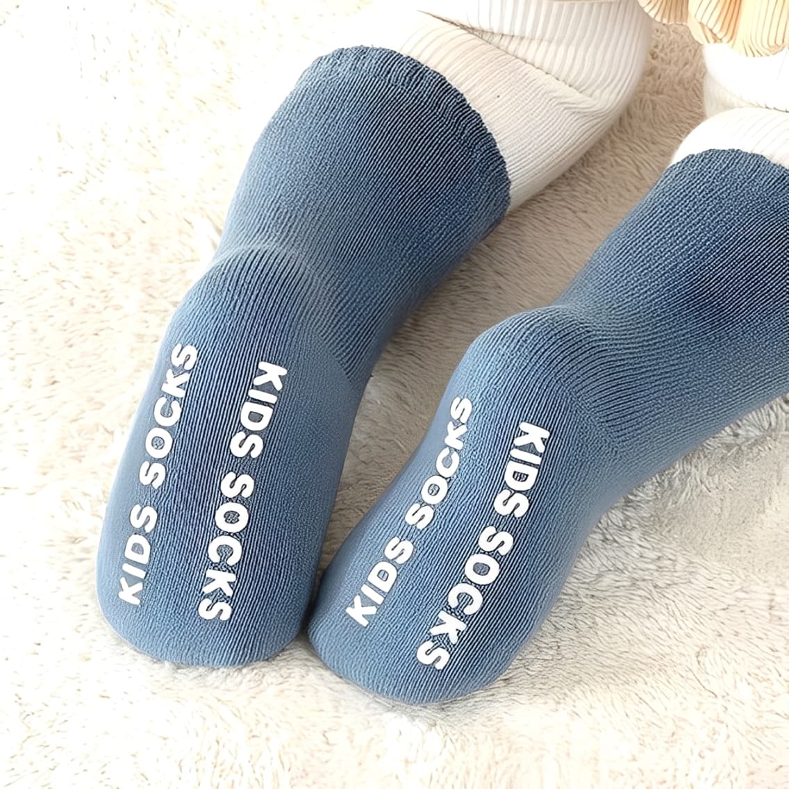 Close-up of toddler blue socks with non-slip lettering for safe indoor wear
