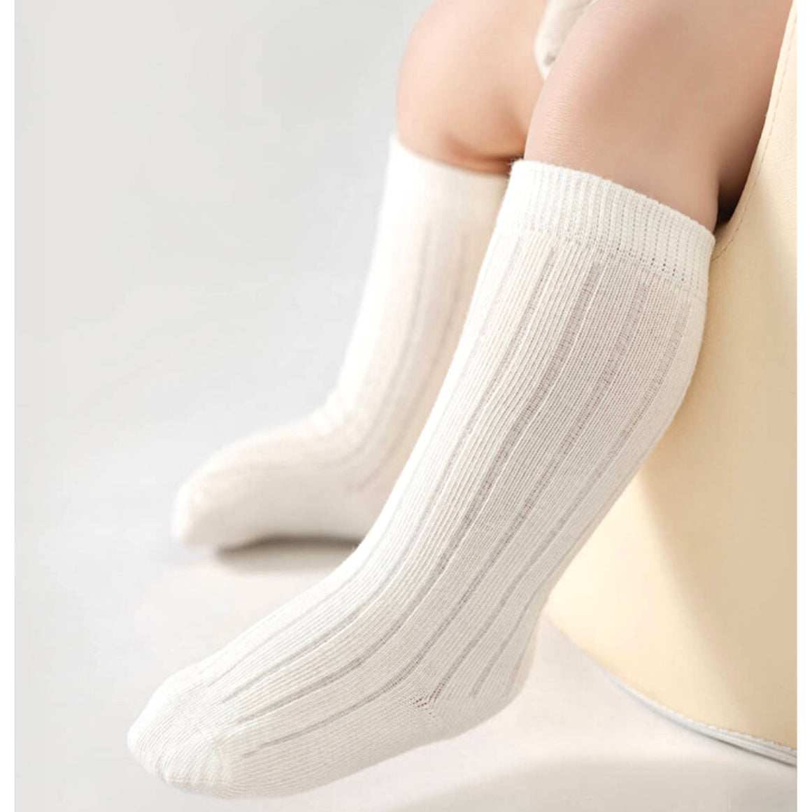 White socks worn by a baby on a light gray background