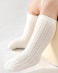 White socks worn by a baby on a light gray background