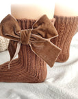 Baby wearing brown velvet bow socks — cozy, stylish cotton baby socks for all seasons.
