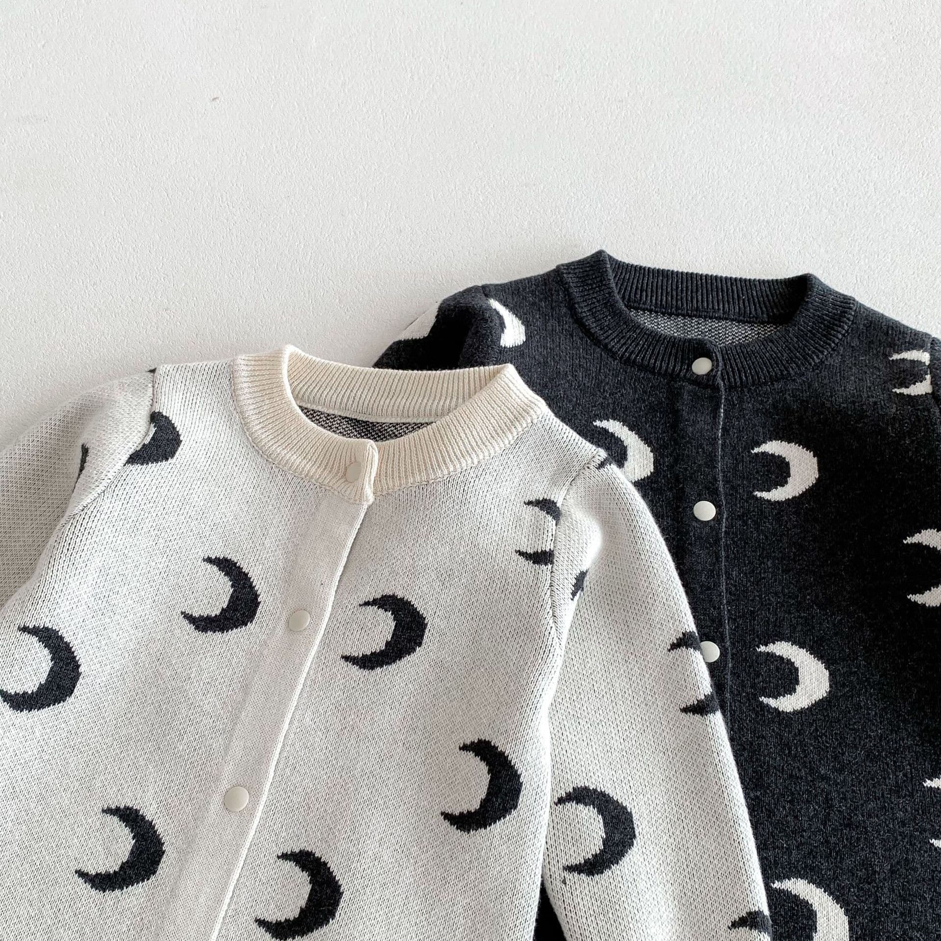 White and dark gray cotton baby rompers side by side – moon pattern unisex jumpsuits.
