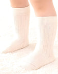 White ribbed cotton socks on child’s feet showing soft stretch and comfortable mid-calf design.