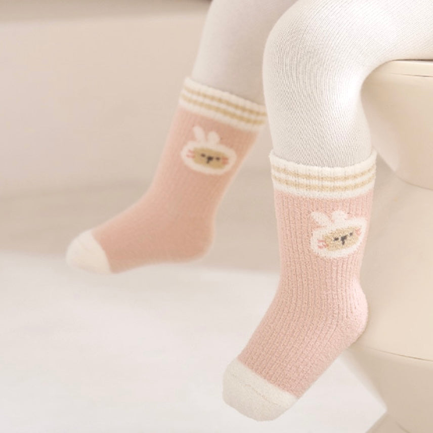 Pink socks with cartoon designs worn by a child on a light background